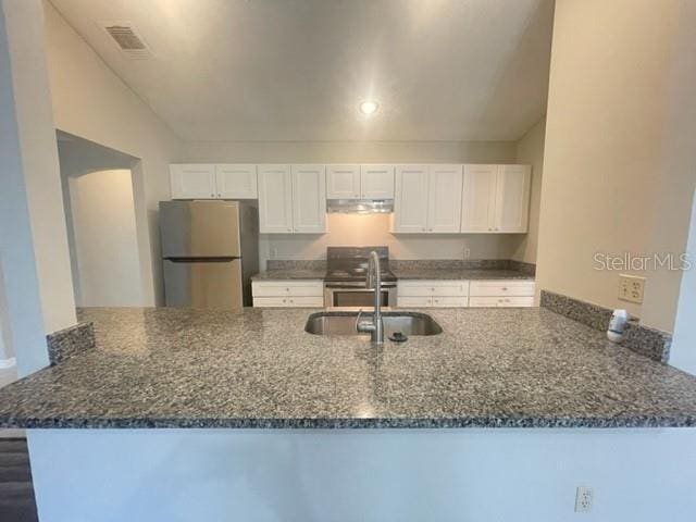 kitchen featuring white cabinetry, kitchen peninsula, dark stone countertops, and appliances with stainless steel finishes