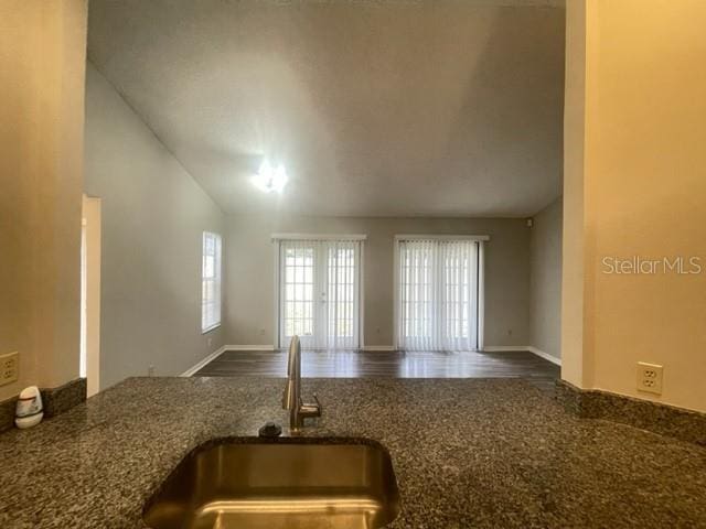 kitchen with lofted ceiling, sink, and dark stone countertops