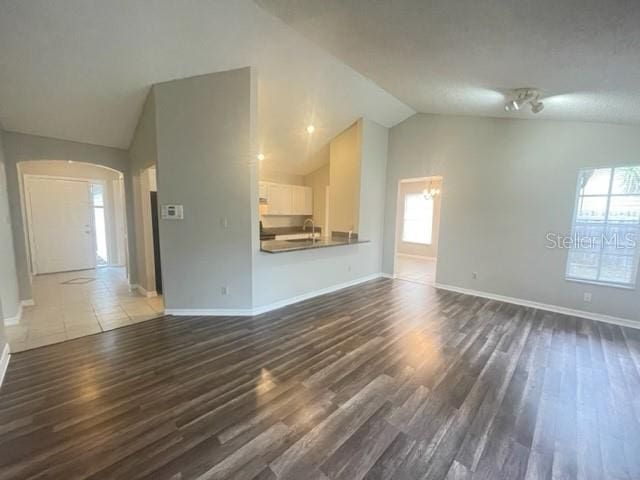 unfurnished living room with sink, vaulted ceiling, and dark hardwood / wood-style floors