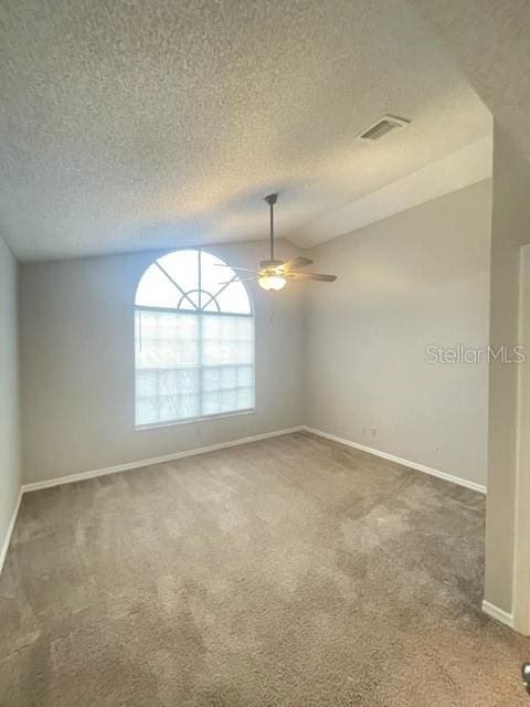 carpeted empty room with a textured ceiling, vaulted ceiling, and ceiling fan