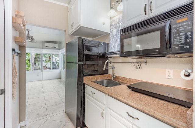 kitchen with light tile patterned flooring, sink, a wall mounted AC, white cabinets, and black appliances