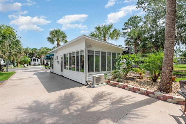 rear view of property with a sunroom and ac unit