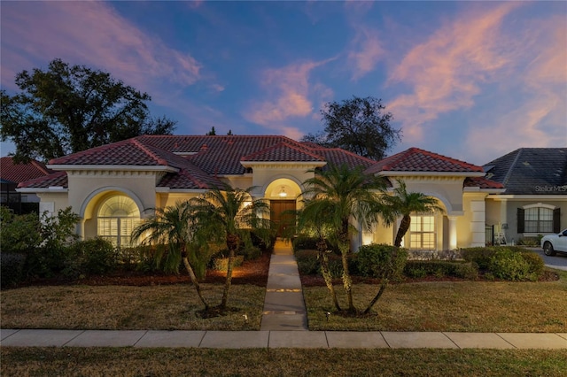 mediterranean / spanish home featuring a lawn