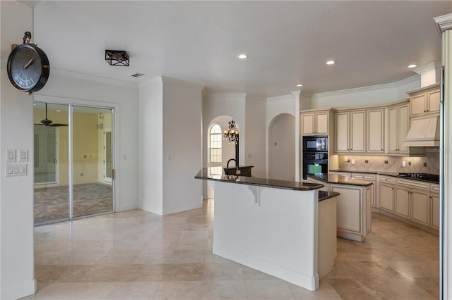 kitchen featuring a breakfast bar area, black appliances, an island with sink, dark stone counters, and backsplash