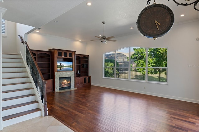 unfurnished living room featuring wood-type flooring, ornamental molding, and ceiling fan