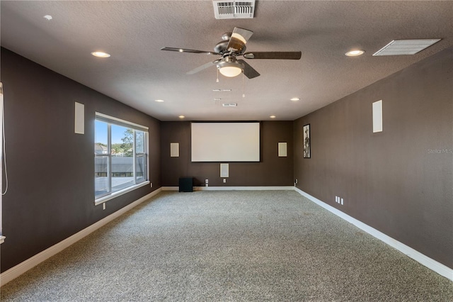 carpeted home theater room with ceiling fan and a textured ceiling