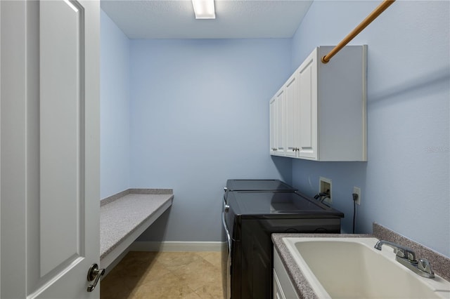 clothes washing area with washing machine and clothes dryer, sink, cabinets, a textured ceiling, and light tile patterned floors