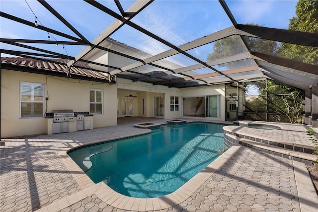 view of swimming pool with an in ground hot tub, an outdoor kitchen, grilling area, and glass enclosure