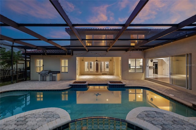 pool at dusk featuring ceiling fan, a patio, an in ground hot tub, area for grilling, and an outdoor kitchen