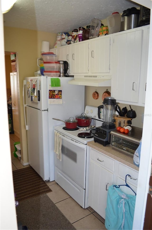 kitchen with white appliances, light tile patterned floors, and white cabinets