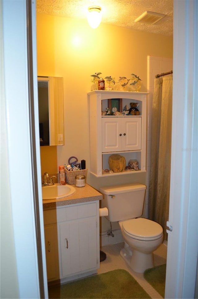 bathroom featuring vanity, curtained shower, toilet, and a textured ceiling