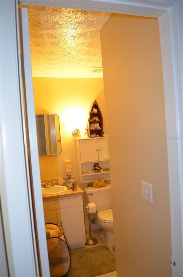 bathroom with vanity, a textured ceiling, and toilet