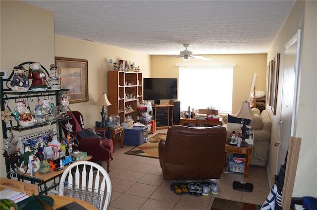 living room with ceiling fan, a textured ceiling, and light tile patterned floors