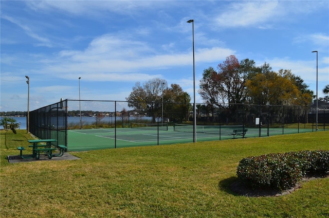 view of tennis court featuring a water view and a yard