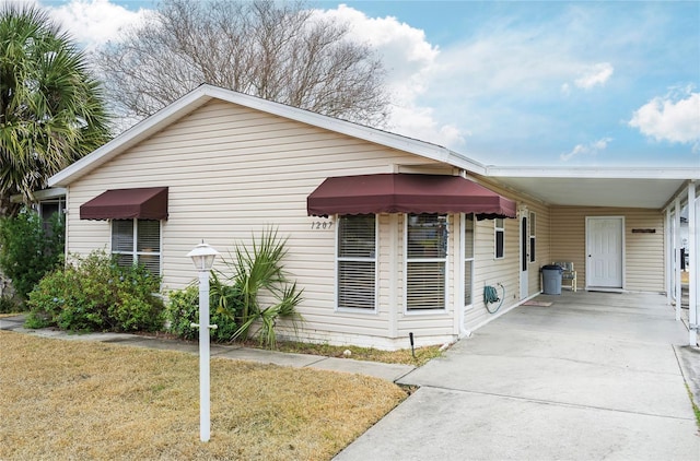 view of side of property with a yard, driveway, and a carport