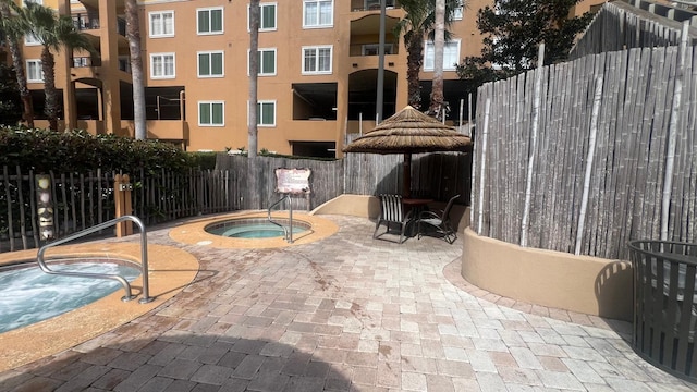 view of patio / terrace with a community hot tub and fence