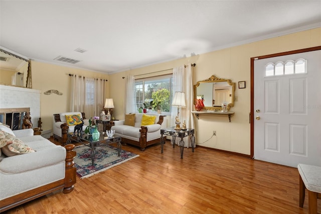 living room featuring hardwood / wood-style flooring, crown molding, and a fireplace