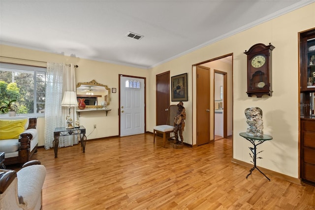 foyer entrance with ornamental molding and light hardwood / wood-style floors