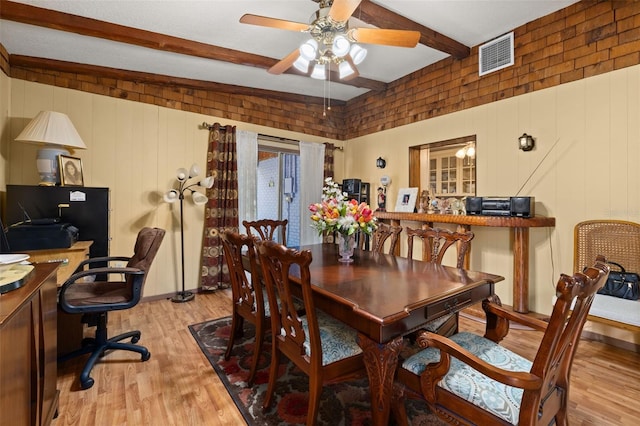 dining room featuring ceiling fan, light hardwood / wood-style floors, and beamed ceiling