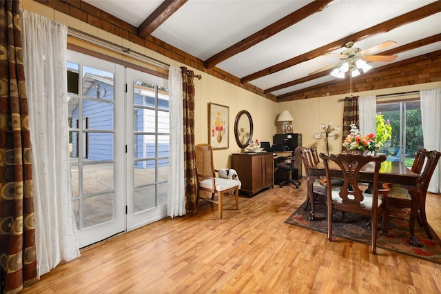 dining space with vaulted ceiling with beams, wood walls, ceiling fan, and light hardwood / wood-style flooring