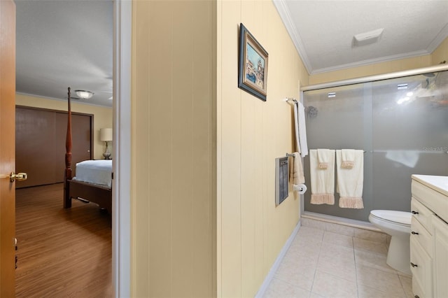 bathroom featuring vanity, ornamental molding, toilet, a shower with door, and tile patterned floors