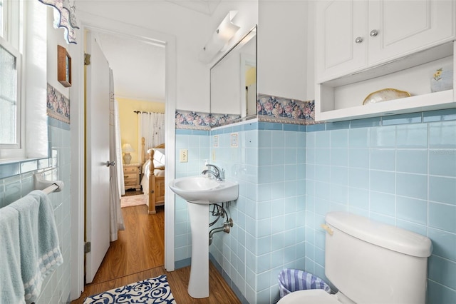 bathroom with wood-type flooring, toilet, sink, and tile walls