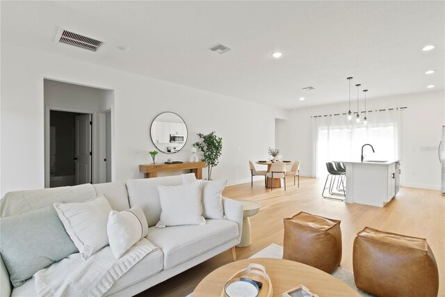 living room with light wood-type flooring, recessed lighting, and baseboards