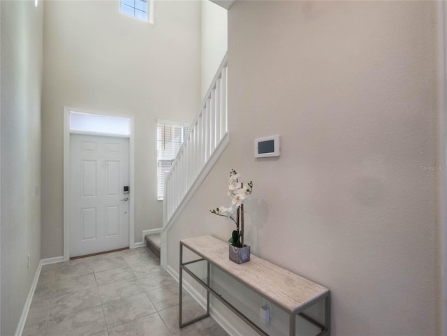 tiled entryway featuring a towering ceiling and a healthy amount of sunlight