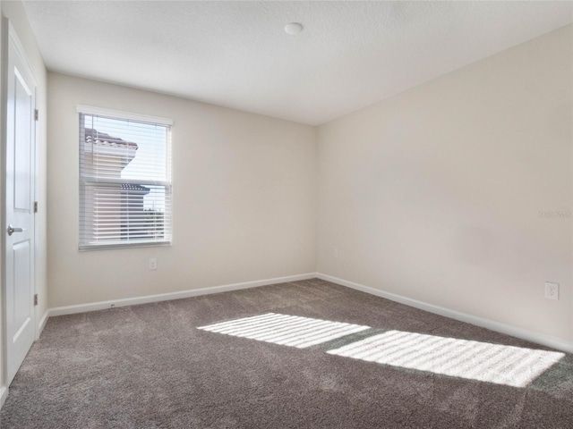 spare room featuring dark colored carpet