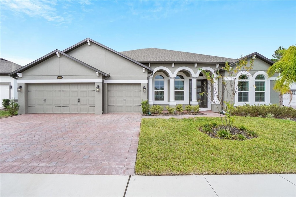 single story home featuring a garage and a front lawn