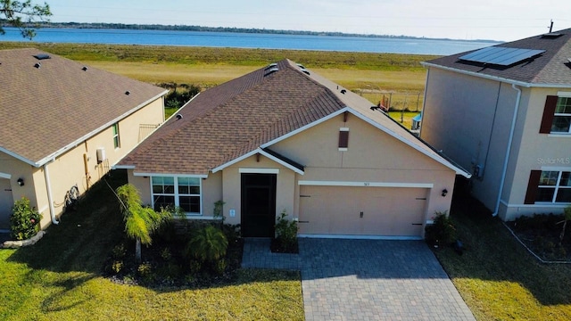 view of front of home with a front yard, solar panels, and a water view