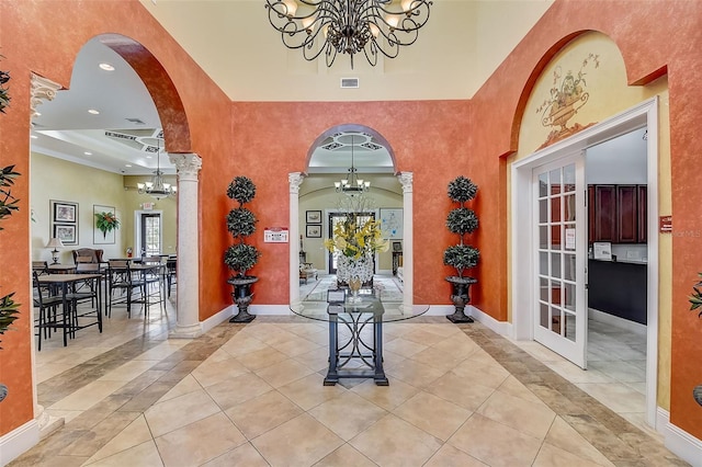 entrance foyer featuring french doors, a towering ceiling, a chandelier, and light tile patterned flooring