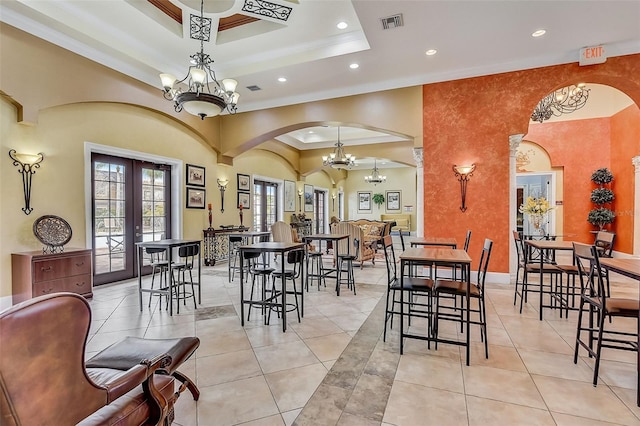 dining area with light tile patterned floors, crown molding, a notable chandelier, french doors, and a raised ceiling