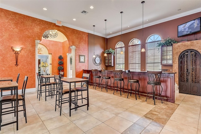 tiled dining room with ornamental molding, bar area, and a high ceiling