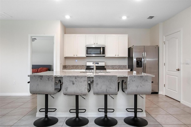 kitchen featuring stainless steel appliances, white cabinetry, a sink, an island with sink, and a kitchen breakfast bar