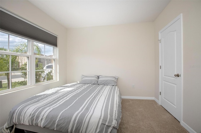 bedroom featuring light colored carpet and baseboards