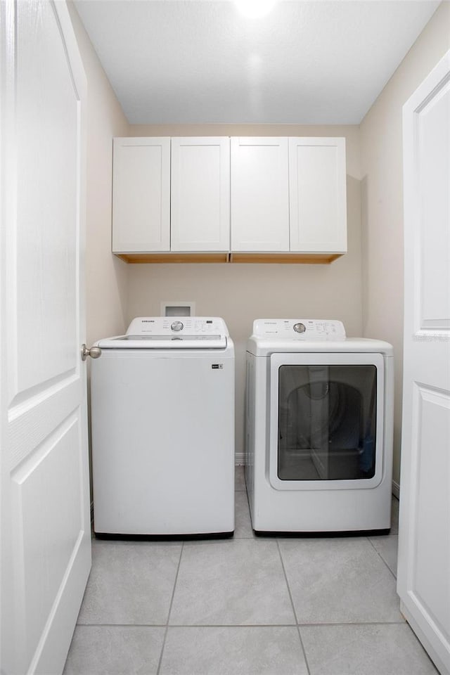 laundry area with cabinet space, washing machine and dryer, and light tile patterned flooring