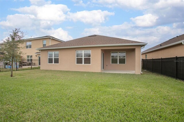 rear view of property featuring a patio, a lawn, fence private yard, and stucco siding