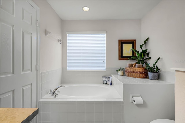 bathroom with vanity and tiled tub