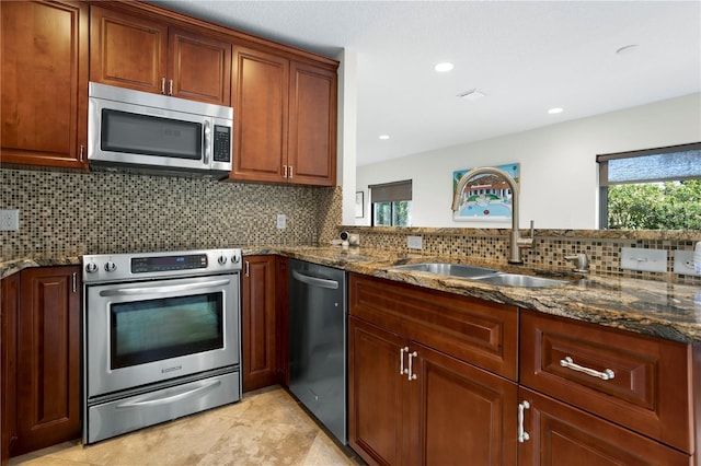 kitchen with sink, dark stone counters, a healthy amount of sunlight, and appliances with stainless steel finishes