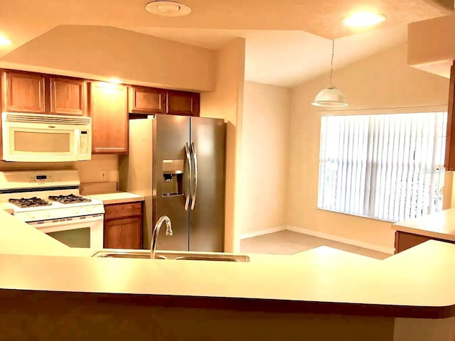 kitchen with lofted ceiling, hanging light fixtures, white appliances, and sink