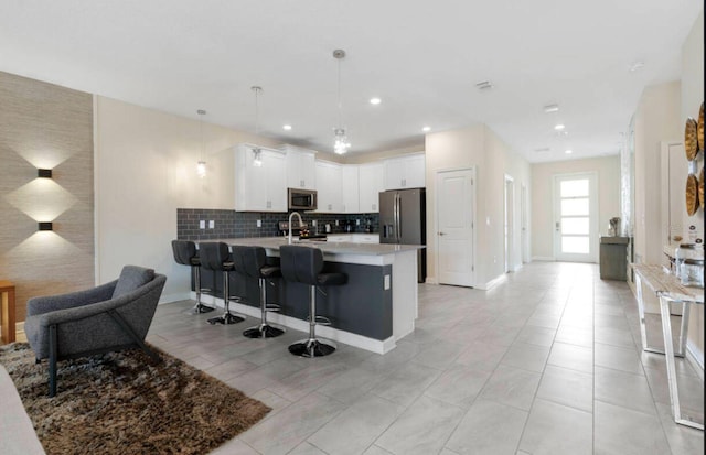 kitchen featuring a breakfast bar area, white cabinetry, stainless steel appliances, decorative light fixtures, and kitchen peninsula