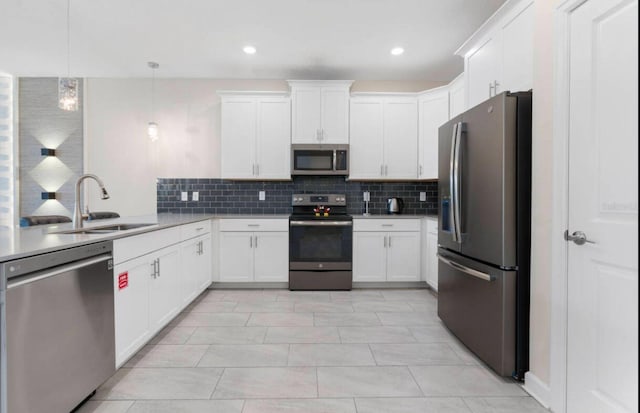 kitchen featuring appliances with stainless steel finishes, white cabinetry, sink, decorative backsplash, and hanging light fixtures