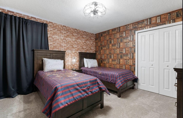 bedroom with light carpet, a closet, a textured ceiling, and brick wall