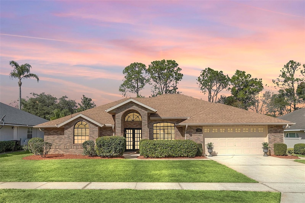 single story home with a garage, a yard, and french doors