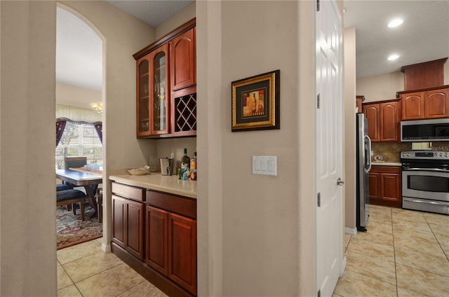 kitchen featuring appliances with stainless steel finishes, light tile patterned floors, and backsplash