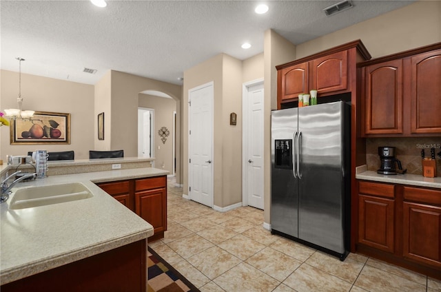 kitchen featuring pendant lighting, sink, light tile patterned floors, stainless steel fridge with ice dispenser, and a textured ceiling