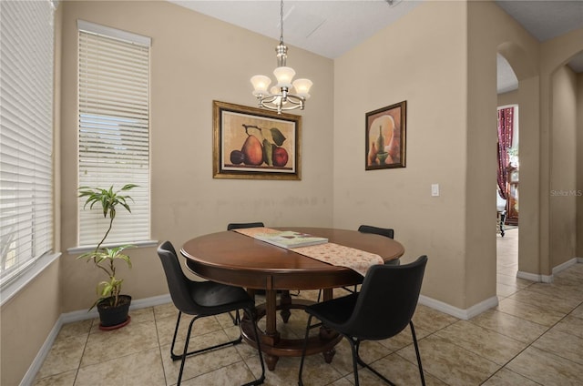 tiled dining space featuring an inviting chandelier and vaulted ceiling