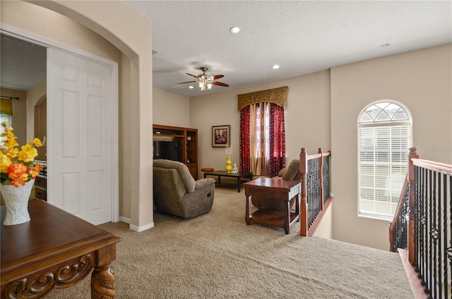 carpeted bedroom featuring ceiling fan, multiple windows, and a textured ceiling