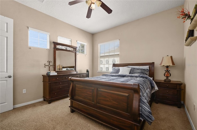 bedroom featuring ceiling fan, light colored carpet, and a textured ceiling